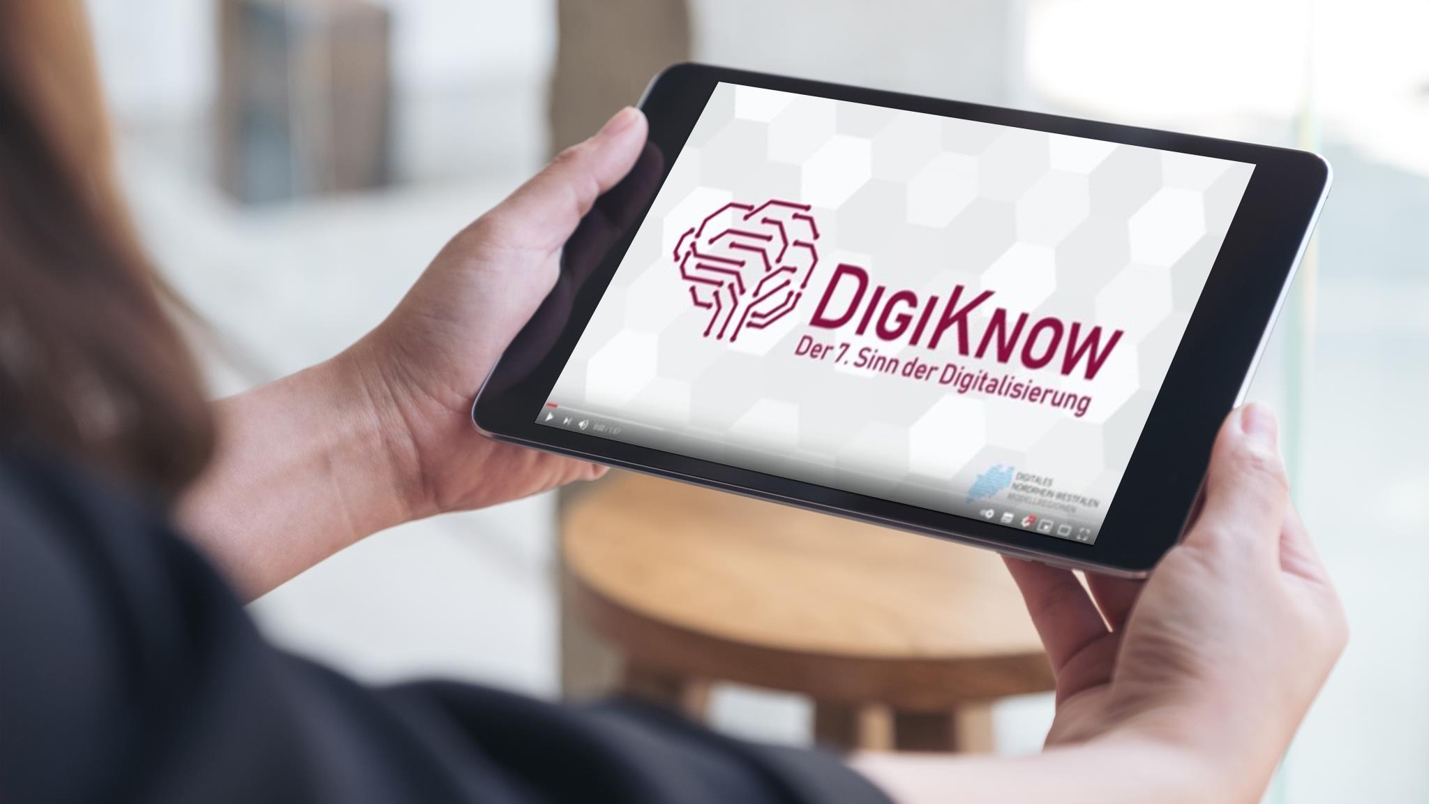 Foto: Person hält Tablet in Hand, auf dem das Logo von DigiKnow abgebildet ist