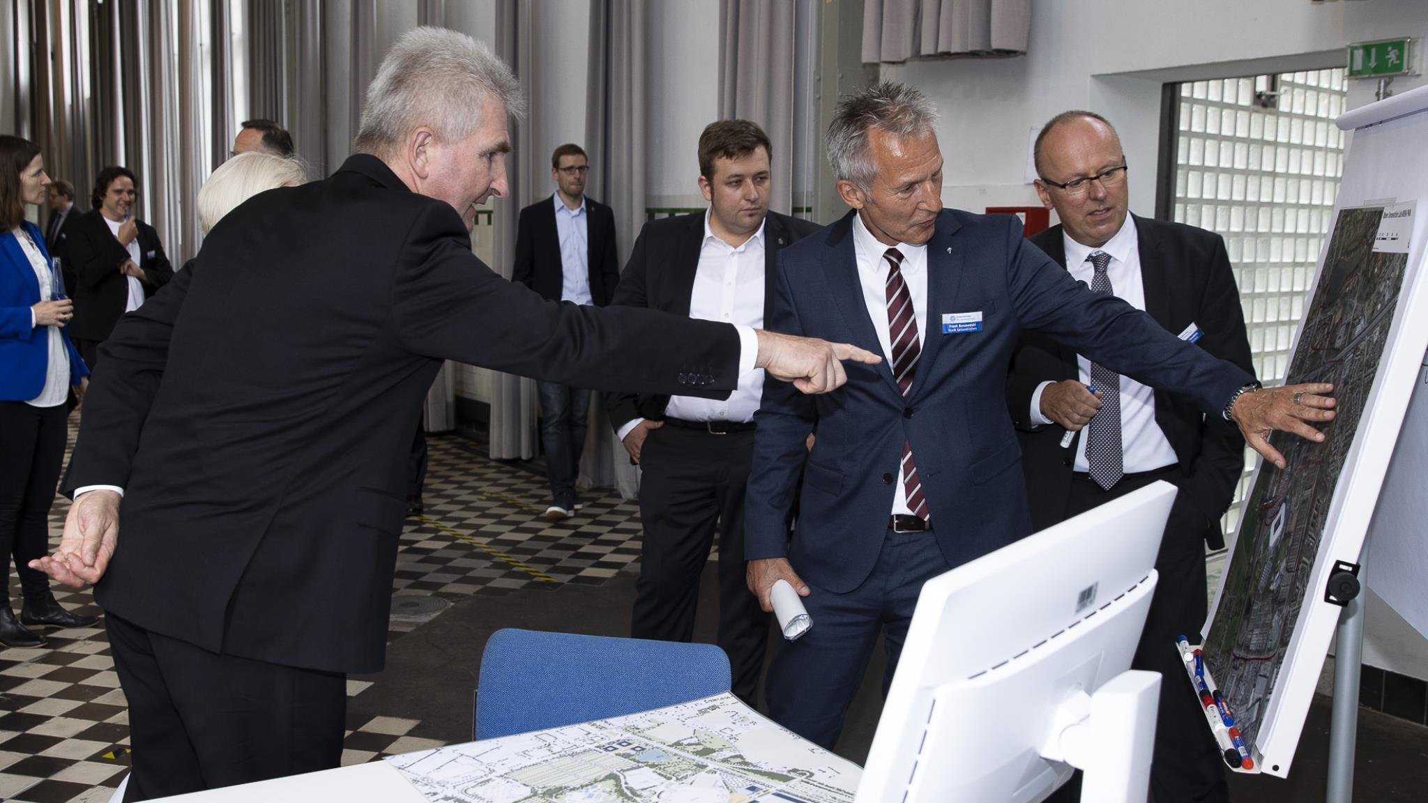 Männer zeigen auf ein Plakat der Vernetzten Stadt Gelsenkirchen.