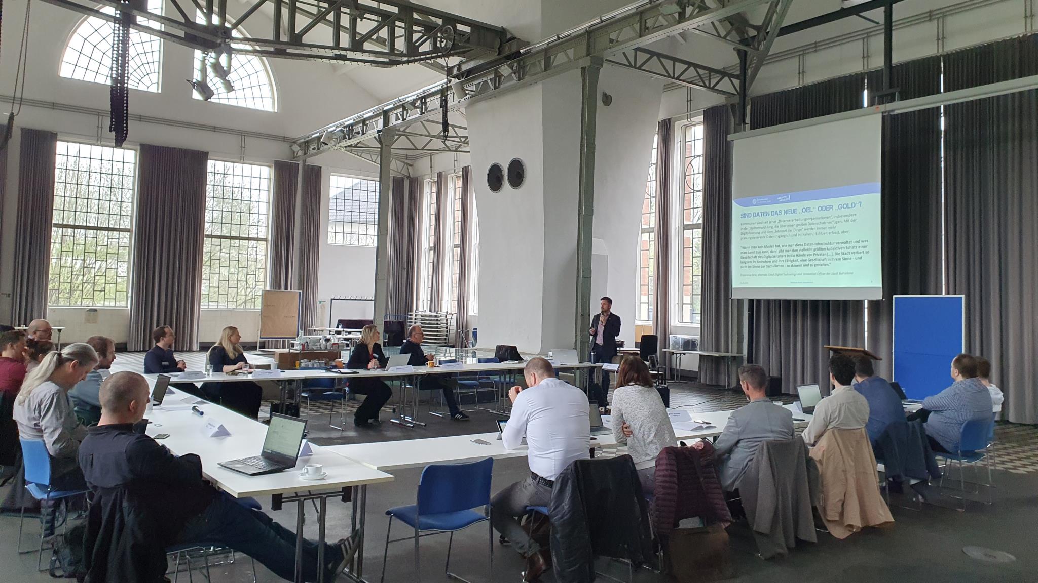 Menschen sitzen an Tisch in U-Form vor Leinwand im stadt.bau.raum Gelsenkirchen