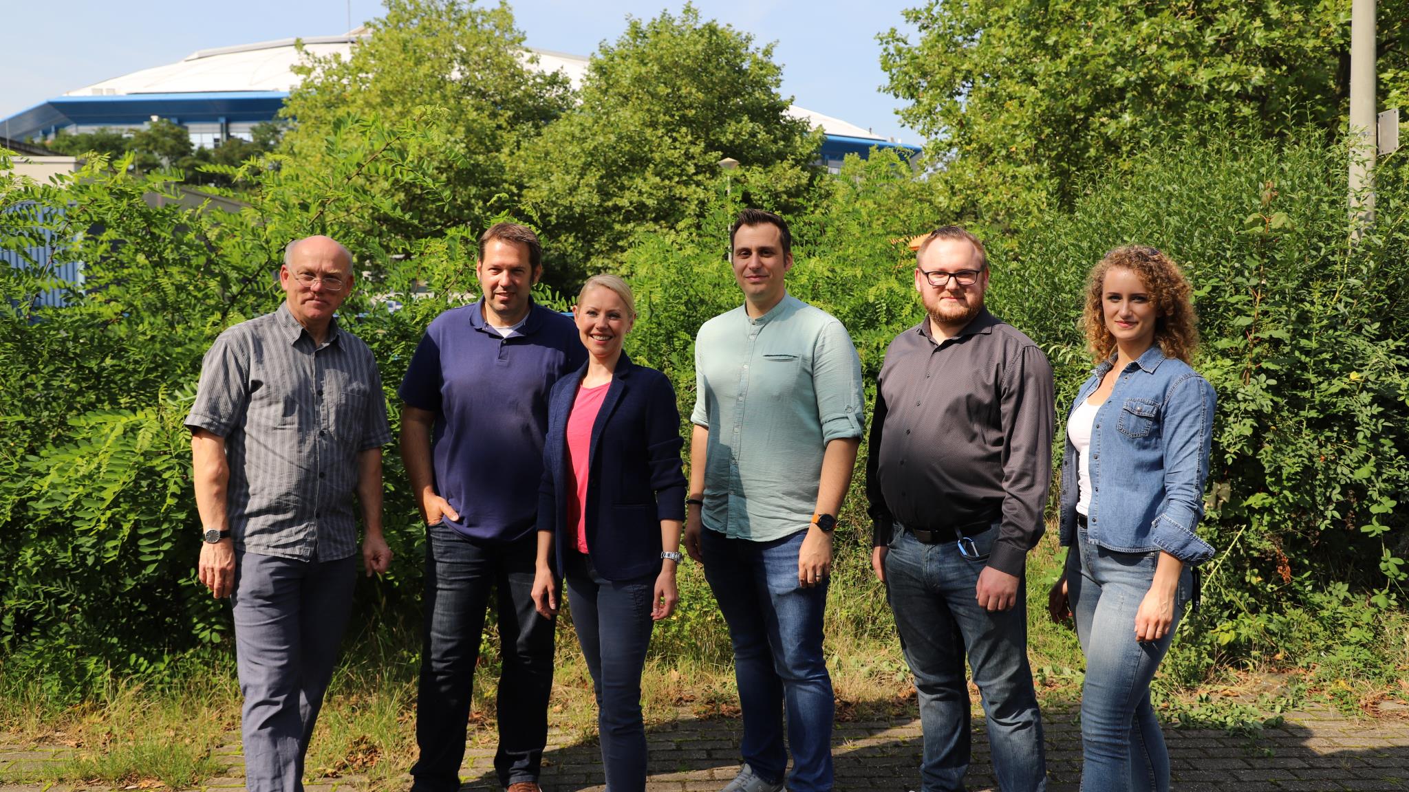 Foto: Sechs Personen stehen nebeneinander, im Hintergrund ist das Dach der VELTINS-Arena.