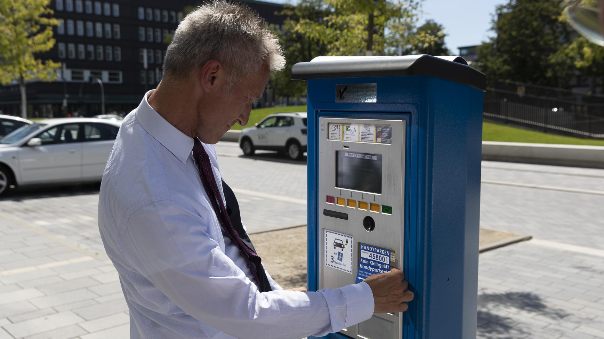 Ein Mann steht vor einem Parkautomaten und studiert die Anleitung