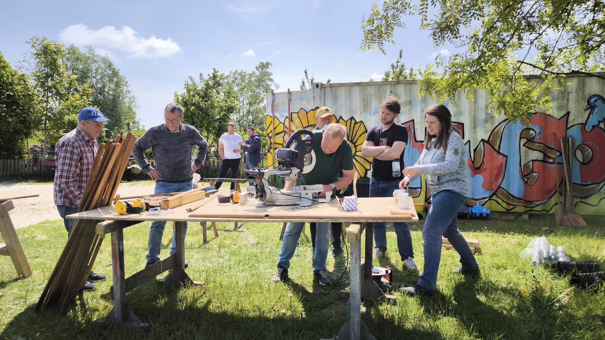 Mehrere Personen stehen umn eine Werkbank herum und bauen etwas.
