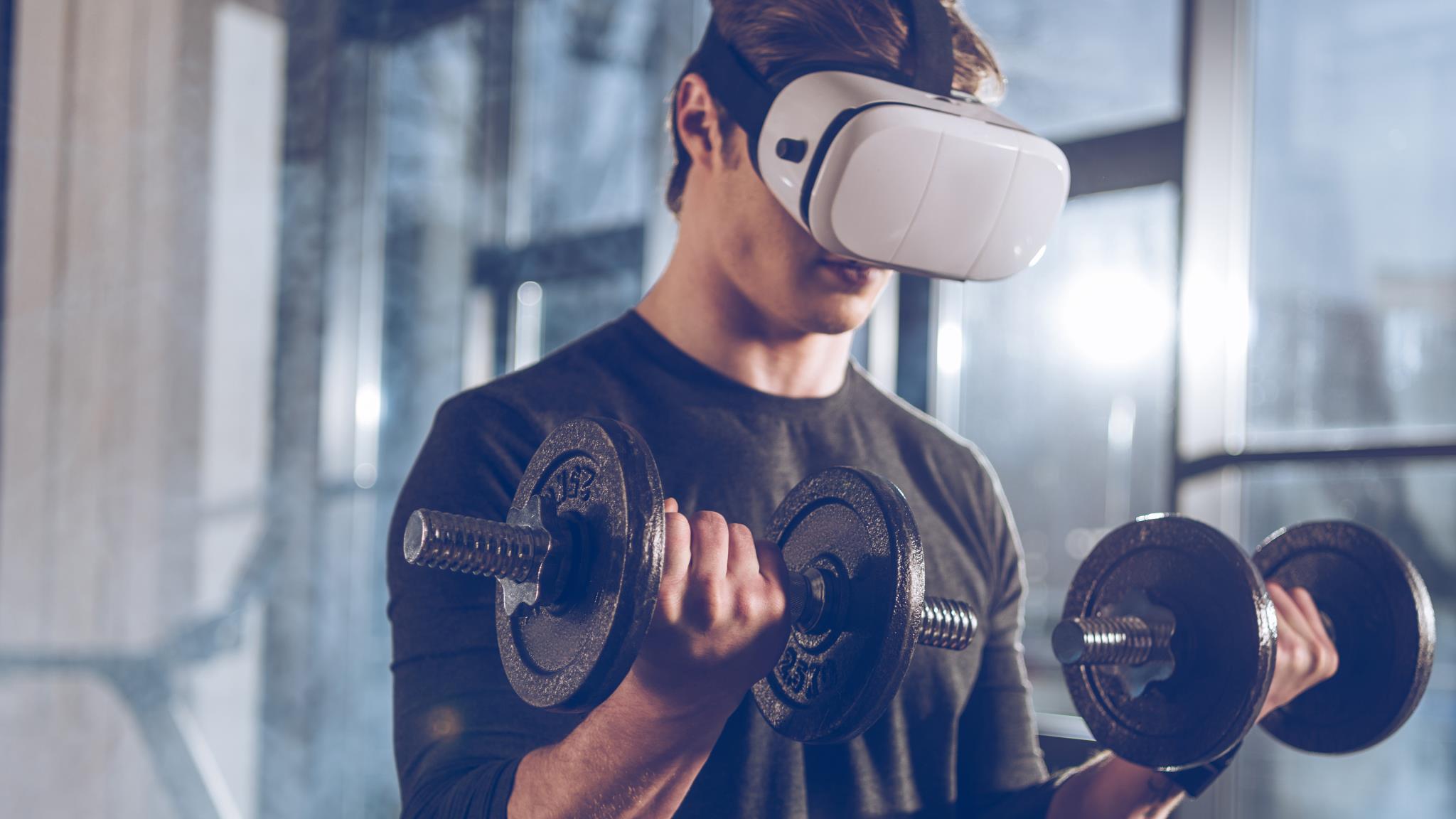 Mann mit VR-Brille trainiert mit Hanteln