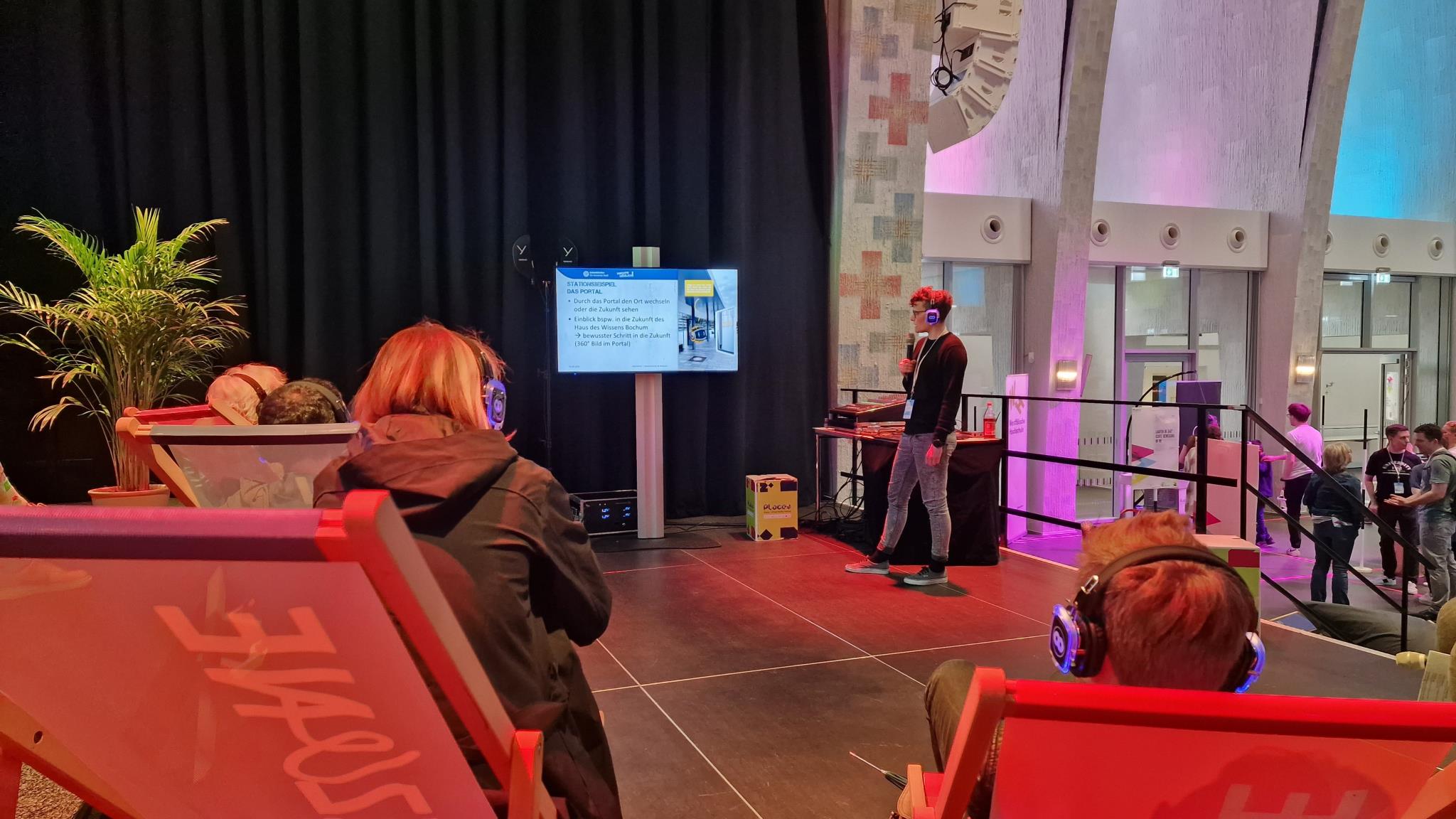 Sabrina Zimmermann steht vor Publikum und Screen und stellt die geplante Digitallinie vor.