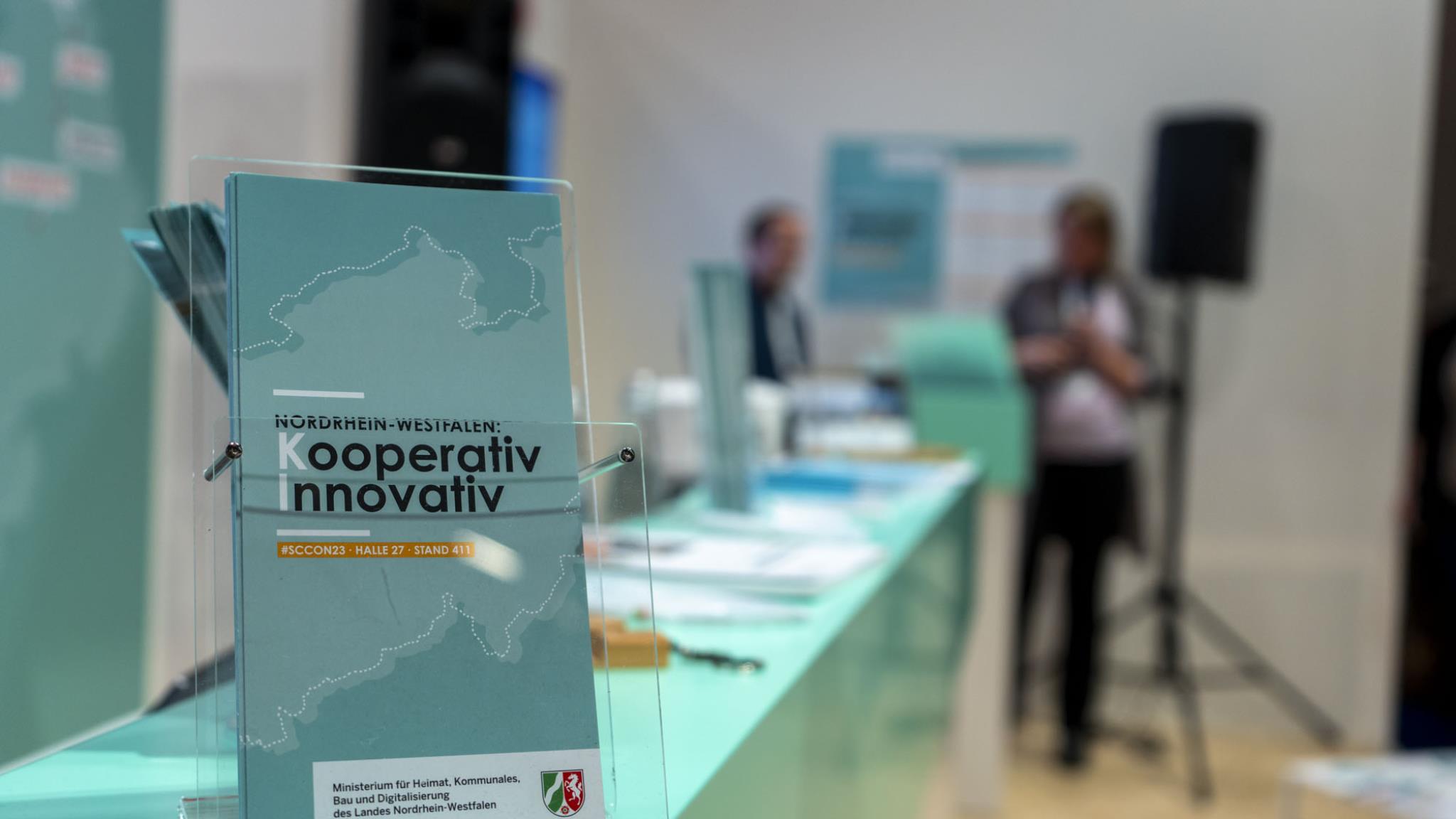 Foto: Flyer des Messestands auf Theke mit verschwommenem Hintergrund